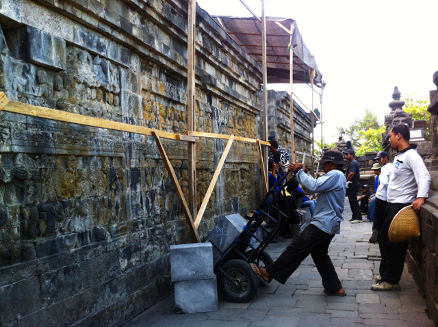 Sejumlah pekerja berada di lorong relief candi yang berubah warna. Terlihat relief candi berwarna kecokelatan. Foto: Nuswantoro