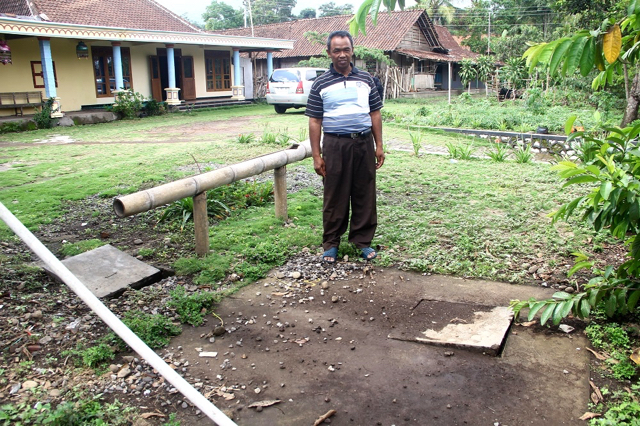 Joko sedang menujukan dan menceritakan cara kerja sumur resapan di depan rumahnya. Foto: Tommy Apriando