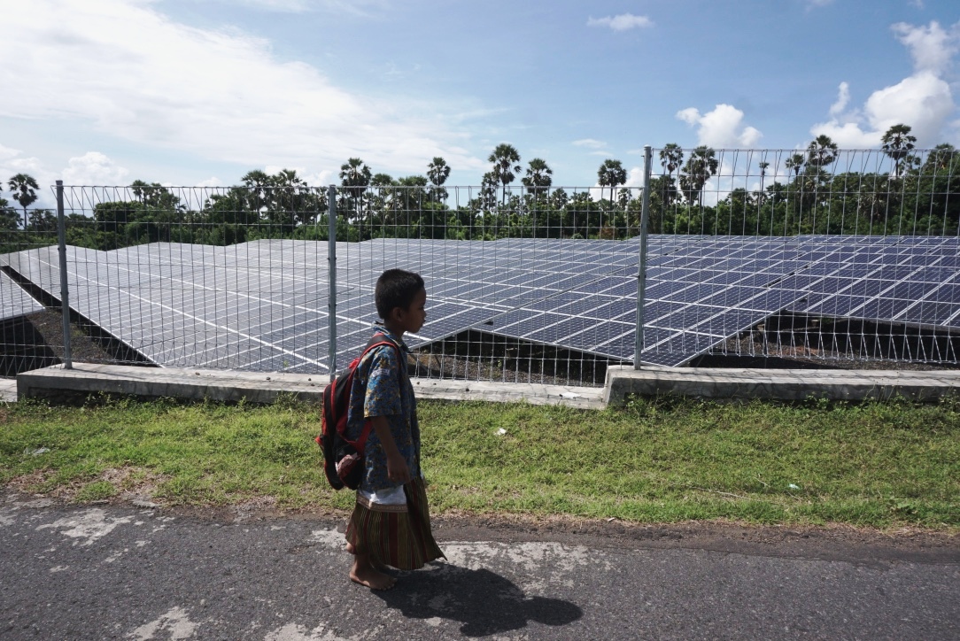 Seorang anak melintas di kompleks PLTS Kubu, Karangasem, Bali, yang kondisinya memprihatinkan dengan banyaknya alat dan panel surya yang rusak. Foto : Anton Muhajir