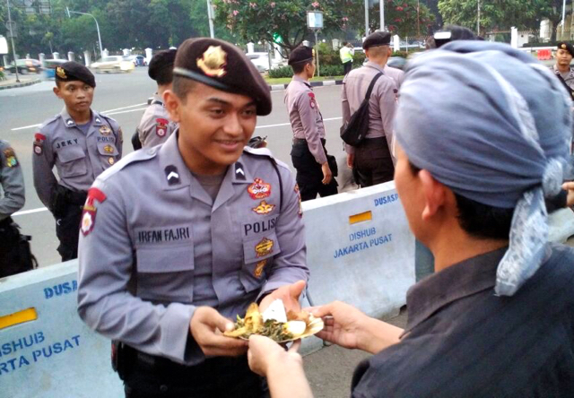 Gunretno, memberikan potongan tumpeng kepada aparat kepolisian yang berjaga-jaga kala aksi mereka. Foto: Jaringan Masyarakat Peduli Pegunungan Kendeng