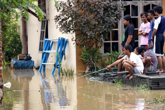 Sebagian warga memancing ikan di halaman rumah yang kebanjiran. Pemerintah perlu membuat data detil mengenai daerah-daerah rawan bencana hingga upaya pencegahan bisa lebih terarah. Foto: Nuswantoro