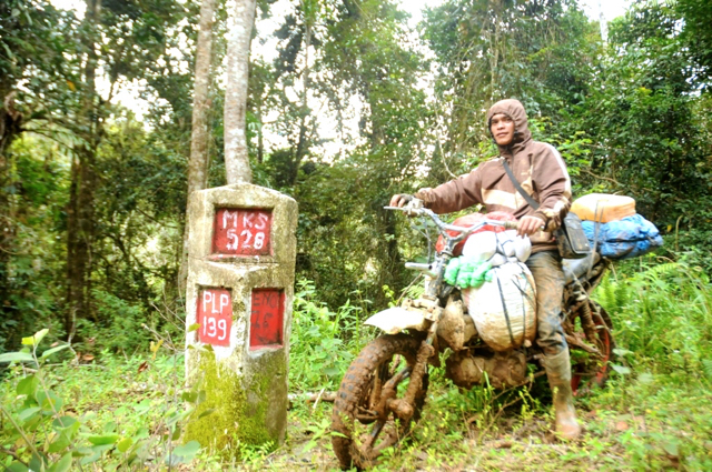 Ian pengemudi ojek berpose di depan tugu jarak dalam perjalanan menuju Seko. Foto: Eko Rusdianto
