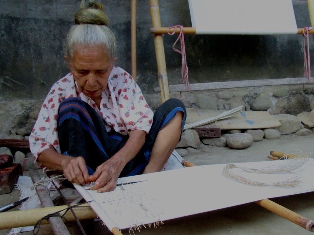 Sisilia Sii sedang mengikat motif pada kain tenun sebelum dicelup untuk diberi warna. Foto: Ebed de Rosary