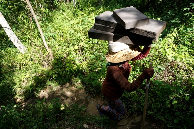 Tukang angkut atau porter perempuan bekerja membawa batu paras dari tempat penambangan ke lokasi penyimpanan melewati jalan cukup terjal di Tukad (sungai) Petanu di Kemenuh, Kecamatan Sukawati, Gianyar, Bali. Foto Anton Muhajir