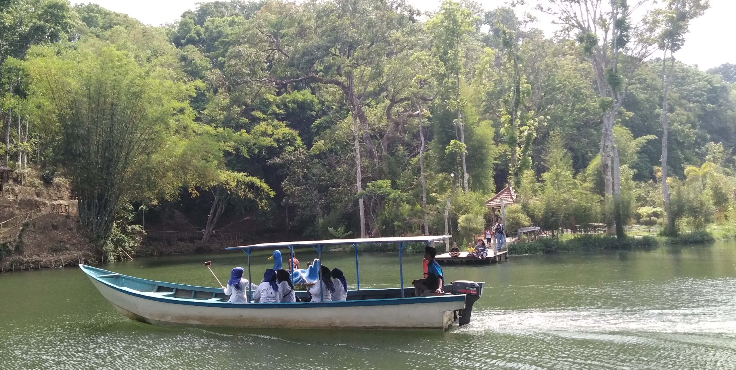 Perahu motor melintas di danau Boonpring, Sumber Andeman dengan hamparan hutan bambu di belakang. Foto: Eko Widianto/ Mongabay Indonesia