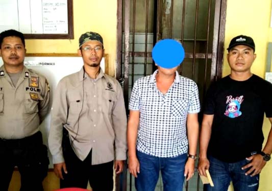 Tersangka, komisaris perusahaan dengan mata ditutup biru, sedang diapit petugas. Foto: Penegakan Hukum KLHK