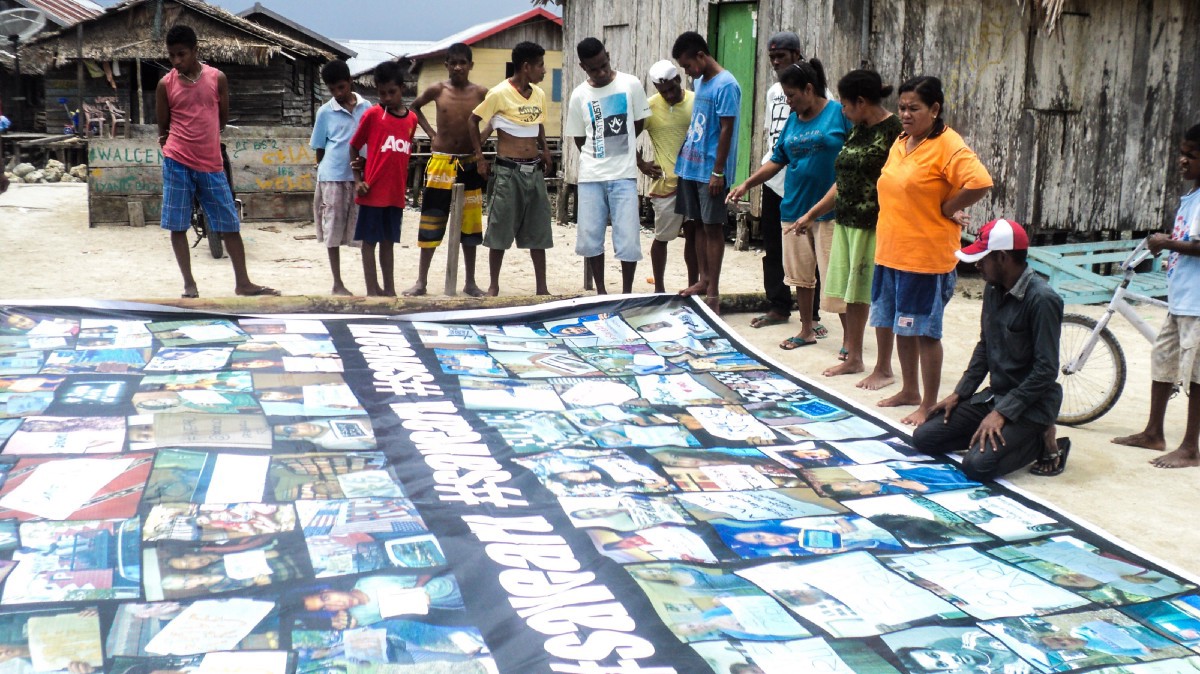 Masyarakat setempat sedang melihat spanduk kampanye di Dobo.