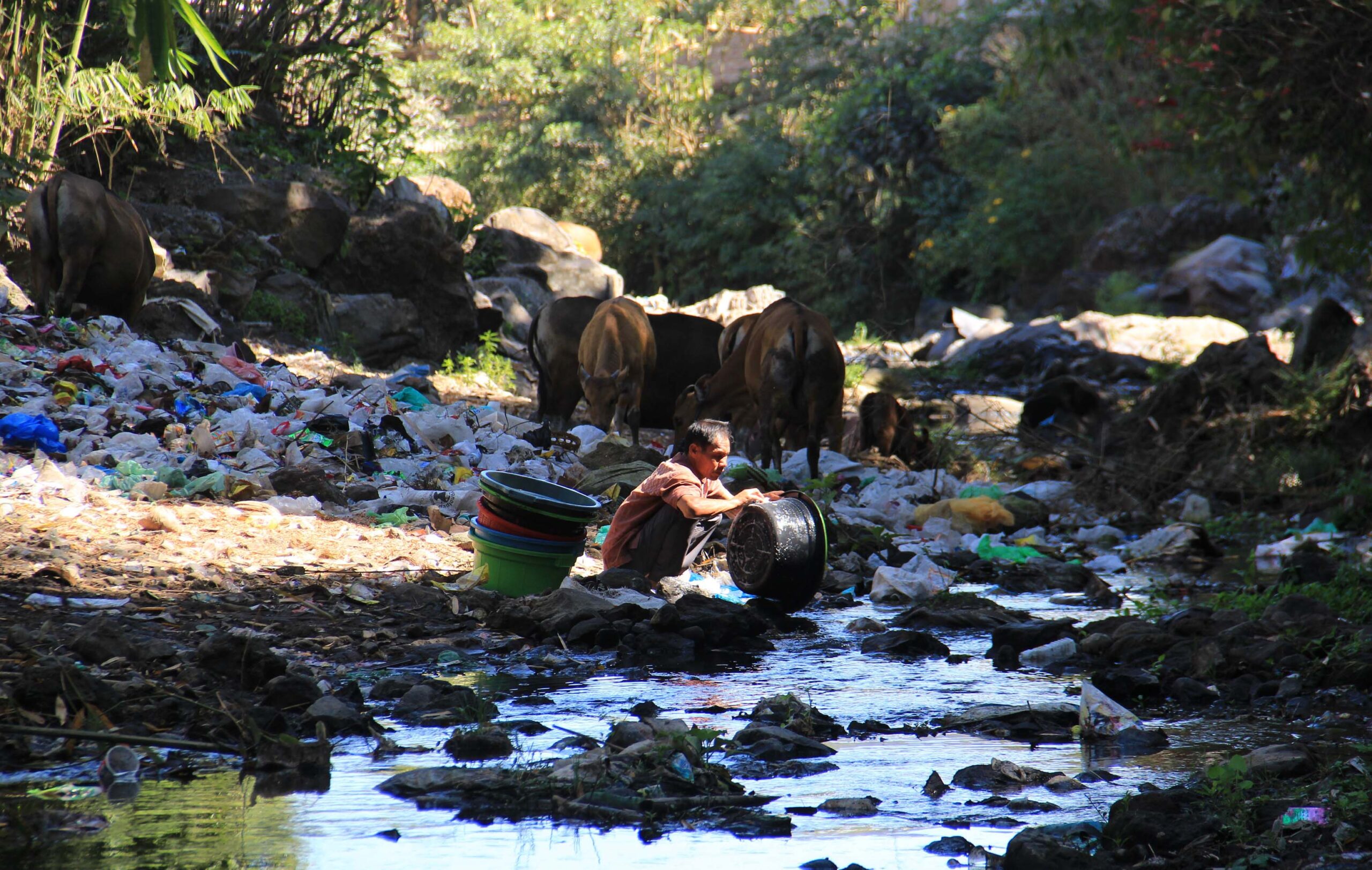 Warga mencuci perlengkapan dapur di aliran sungai yang penuh sampah plastik. Air sungai ini masih jernih tetapi terlihat kumuh karena banyak sampah.Foto: Fathul Rakhman/Mongabay Indonesia