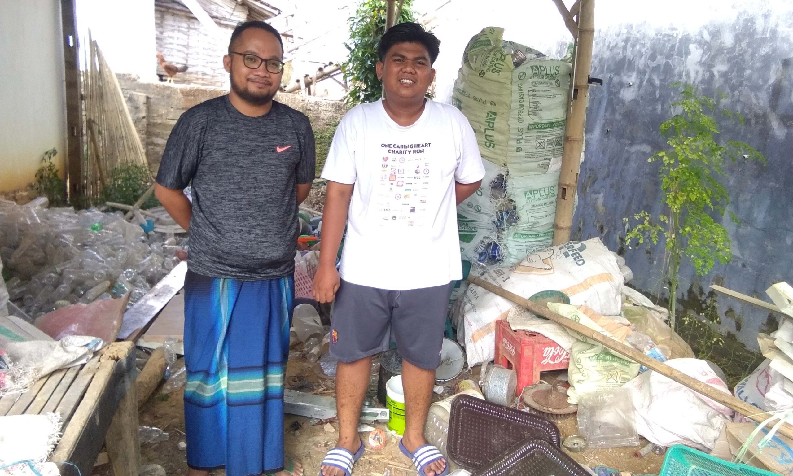 Ihsan (kaos hitam) di tempat pemilahan sampah. Foto: Gafur Abdullah/ Mongabay Indonesia