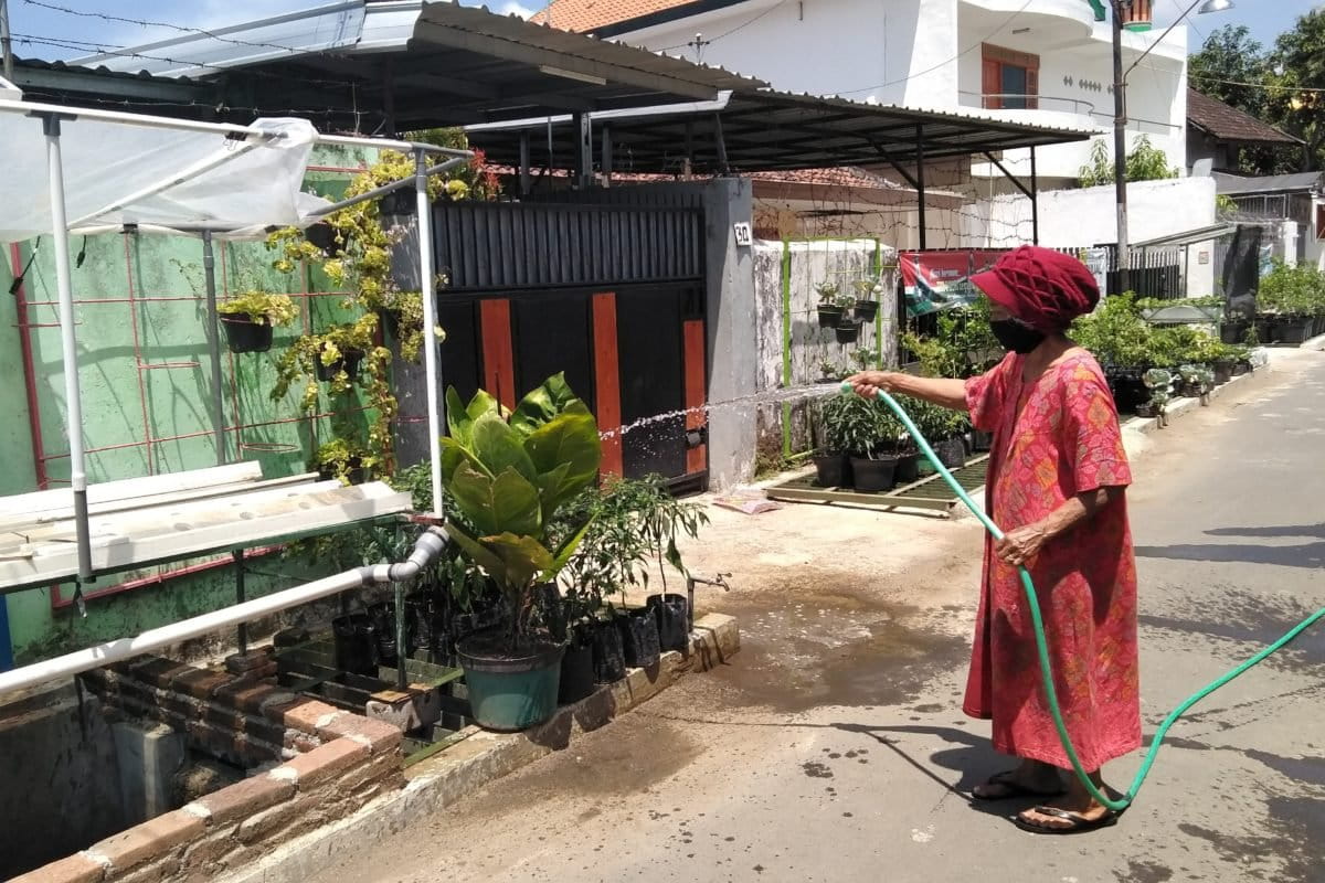 Warga Glintung menyirami tanaman di depan rumah mereka. Foto: Eko Widianto/ Mongabay Indonesia