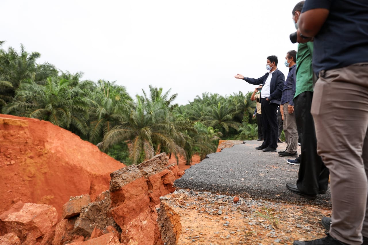 Gubernur Kepri Isdianto saat meninjau jalan putus setelah kawasan ini diguyut hujan cukup lama. Ruas jalan tersebut diapit oleh kebut sawit perusahaan Tirta Madu, perusahaan yang memiliki luas sawit terbesar di Provinsi Kepulauan Riau. Sumber foto: Humas Pemprov Kepri 