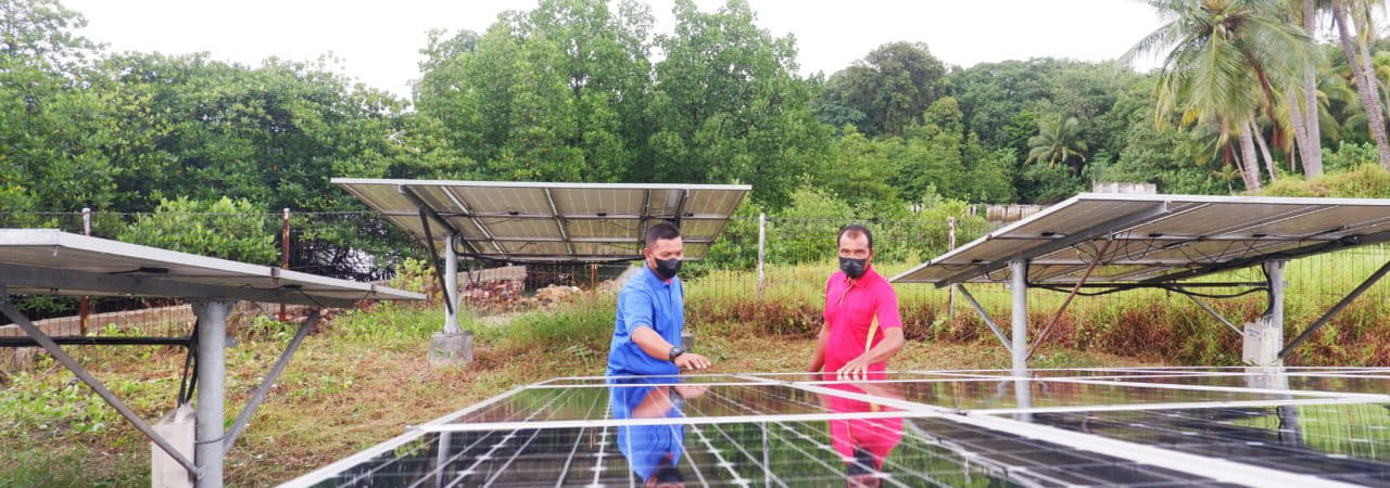 surya mecan 14. Rizwan (baju biru) memperlihatkan atap panel surya PLTS komual di Pulau Mecan, Belakang Padang.