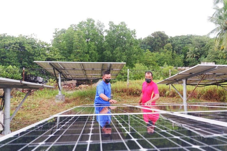 surya mecan 14. Rizwan (baju biru) memperlihatkan atap panel surya PLTS komual di Pulau Mecan, Belakang Padang.