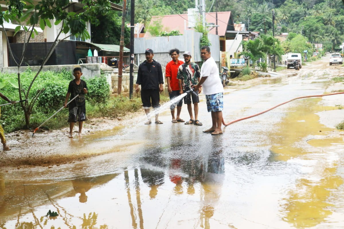 Warga Jondul Rawang menyiram lumpur bekas banjir di jalan utama pada Kamis (30092021)edit.jpg