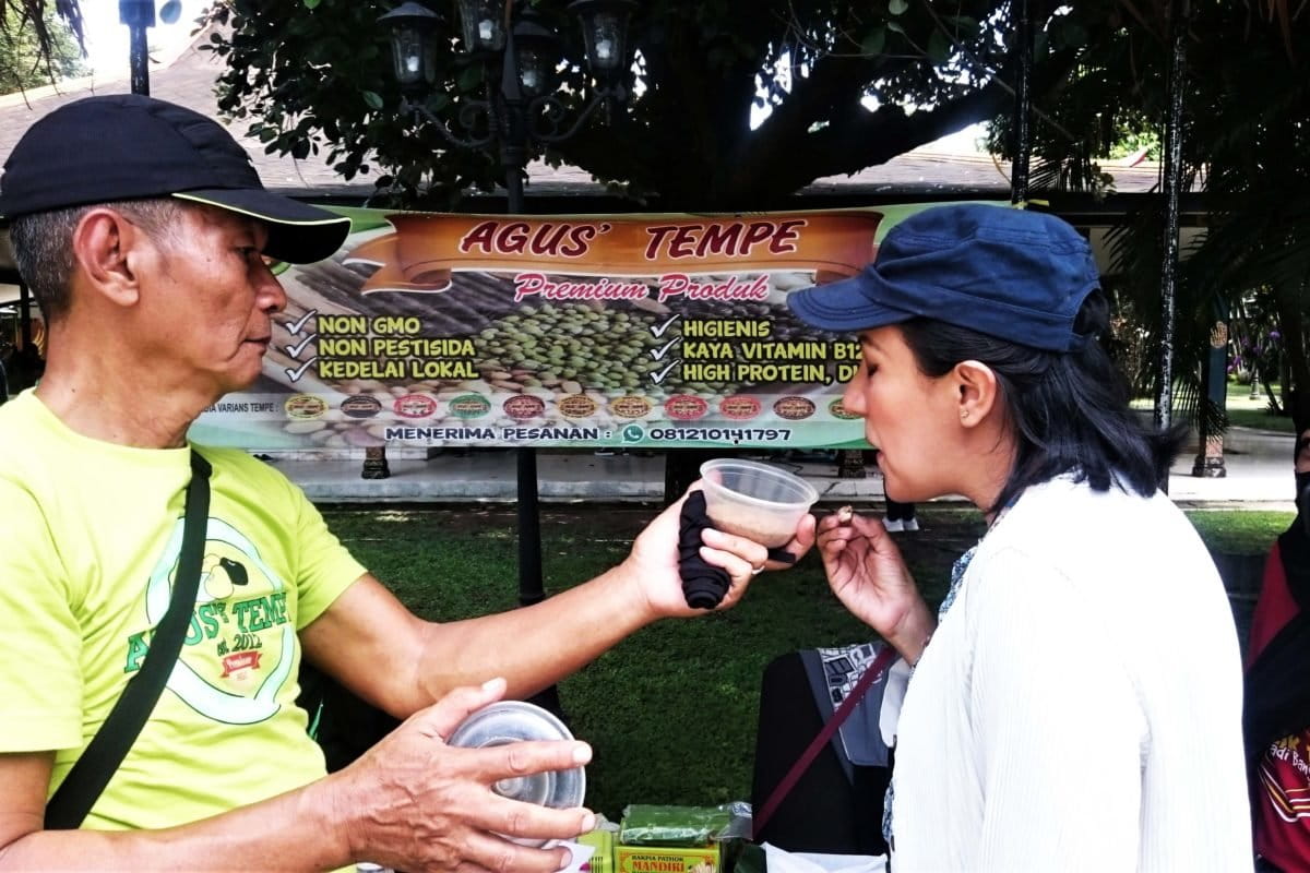 Agustinus, memperlihatkan bahan tempe organik kepada Claudia, mahasiwa di Jogja, asal Meksiko yang menyukai tempe. Foto: Nuswantoro/ Mongabay Indonesia