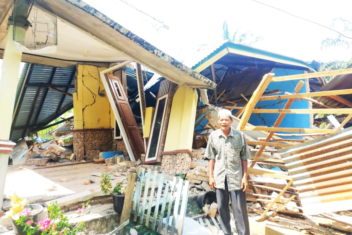 Seorang pria paruh baya berdiri di depan reruntuhan rumahnya. Data sementara kerugian material tercatat total jumlah rumah rusak mencapai 1.783 unit. Sebanyak 1.754 unit masih dalam proses verifikasi tingkat kerusakan, sedangkan sisanya teridentifikasi rusak berat 2 unit, rusak sedang 20 unit dan rusak ringan 7 unit. Foto: Vinolia/ Mongabay Indonesia