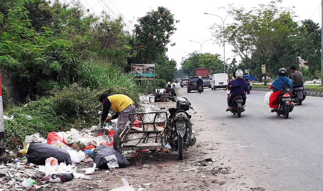 Pemulung sampah mencari sampah yang bisa dijual kembali di tepi jalan di Pekanbaru, Riau. Masih banyak warga membuang sampah sembarangan di tepi-tepi jalan hingga sampah pun jadi persoalan di kota ini. Foto: Suryadi/ Mongabay Indonesia