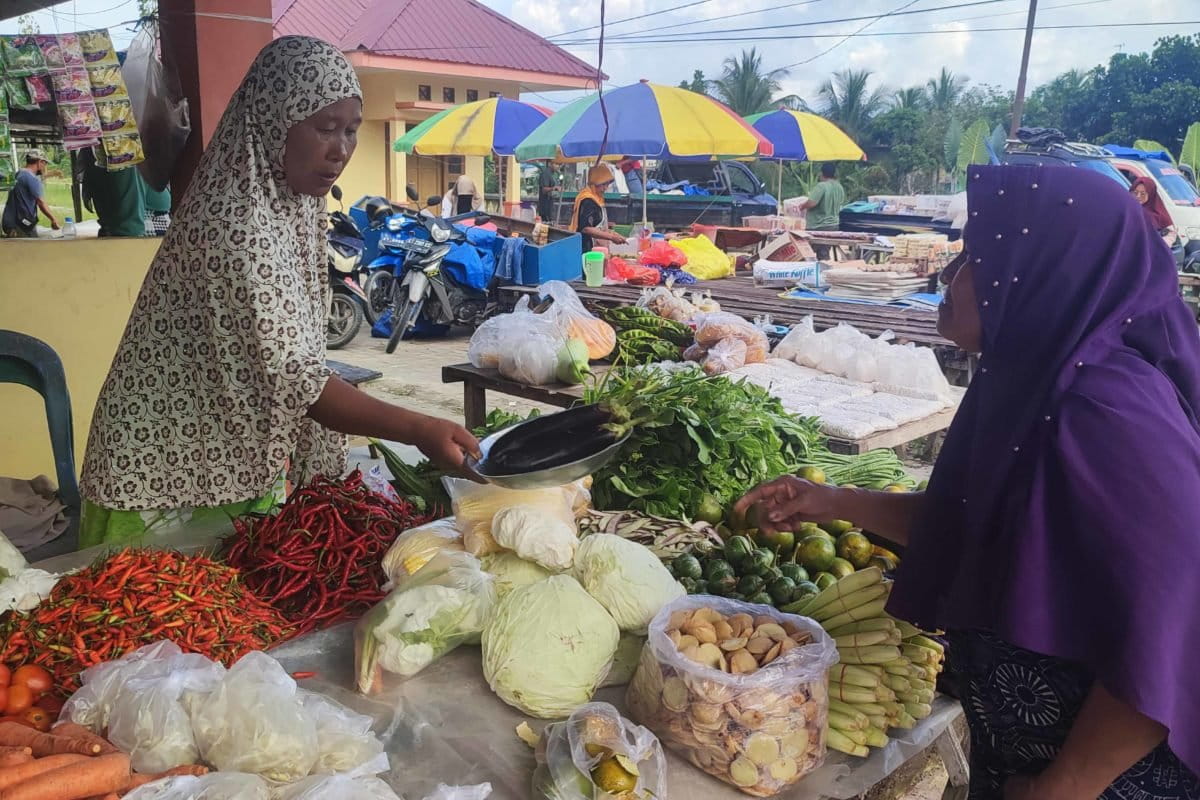 Kusmiatun, perempuan berusia 54 tahun sedang merapikan jualan sayur dan buah. 