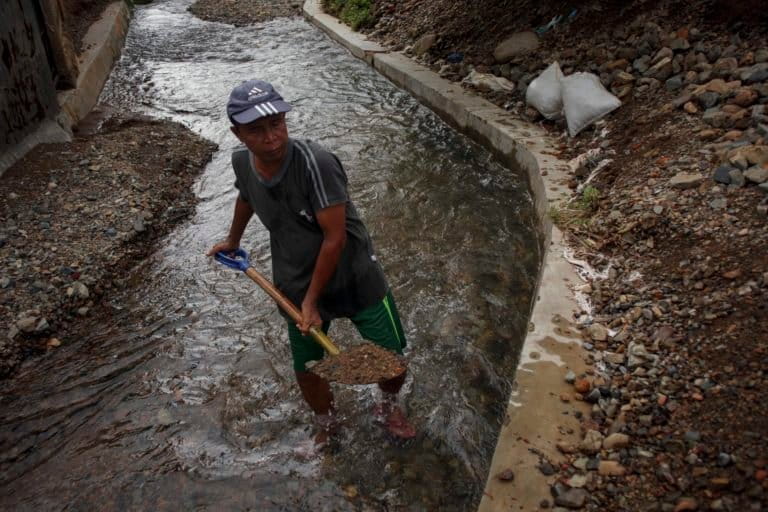  Nasrulwarga Teluk Kabung Tengah menggali bebatuan yang menumpuk di selokan. Foto: Jaka HB/ Mongabay Indonesia