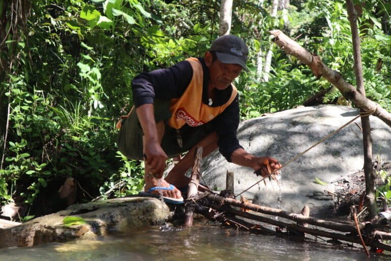 Masyarakat Adat Moa sedang membersihkan sungai yang digunakan untuk pembangki listrik dengan kincir air. Merekalah para penjaga hutan. Bagaimana dampak terhadap masyarakat adat ketika perdagangan karbon datang? Foto: Sarjan Lahay/ Mongabay Indonesia