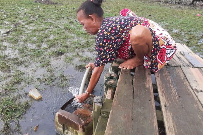 Dahniar, memompa sumur bor sebelah rumahnya. Air keluar memang putih dan jernih tetaoi bau menyengat dan berubah jadi kuning setelah beberapa menit. Foto: Suryadi/ Mongabay Indonesia