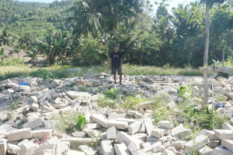 Opan Munu berdiri di puing-puing rumahnya yang hancur diterjang banjir bandang. Foto_ Franco Bravo Dengo