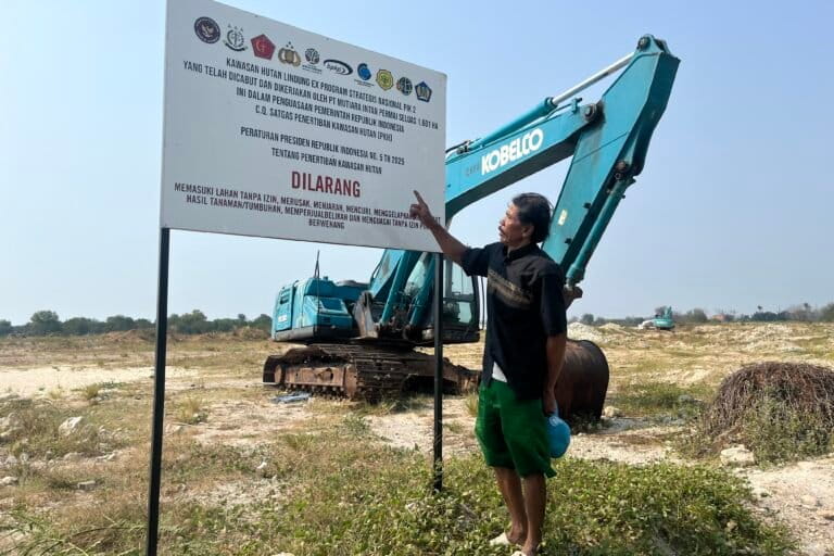 Dadang berdiri di depan plang di kawasan pengambil alihan kawasan hutan lindung ex program strategis nasional PIK 2 yang berada di Kabupaten Tangerang. Foto: Anggita Raissa/Mongabay Indonesia