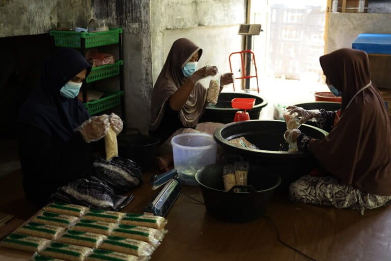 Jamilah, Samiyati, dan Nurmawati (kiri ke kanan), perajin tempe Rumoh Tempe Nusa sif siang, sedang melakukan proses peragian dan pengemasan tempe koro. Foto: Nurul Hasanah/Mongabay Indonesia